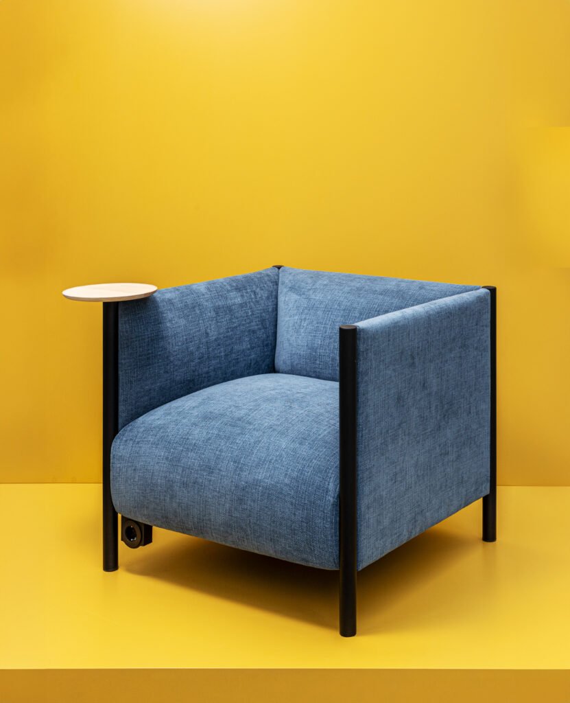 Acercamiento de sillón Infiniti Desing forrado con charola para colocar vaso.