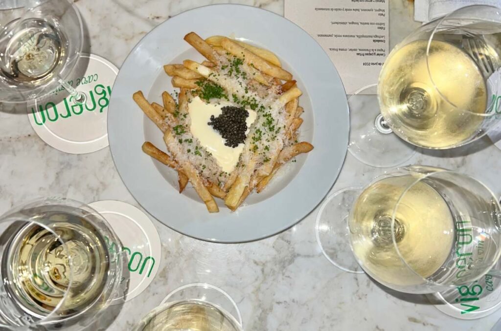 Papas fritas con caviar al centro y vino blanco de Vigneron en Ciudad de México. 